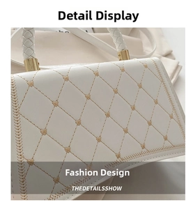 Detail of white quilted handbag featuring gold heart embroidery and woven top handle