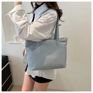 Blue nylon tote bag detail showing large capacity and durable shoulder straps on a model