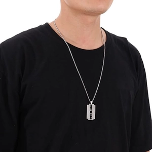 Detail of silver stainless steel razor blade pendant on a long sweater chain