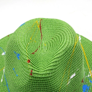 Close-up of bright green straw hat featuring artistic colorful paint splatter texture