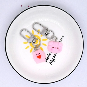 Cute pink resin pig keychains set of two on a decorative white sun pattern plate