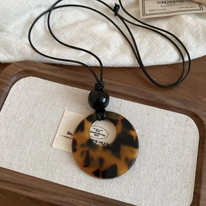Detailed view of a vintage tortoiseshell resin pendant on a black cord necklace