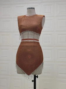 Dettaglio del set due pezzi in maglia con frange di strass e orlo asimmetrico in rame