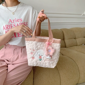 Close-up of quilted floral tote bag with cute dog embroidery and plush flower charm
