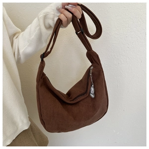 Detailed texture of brown corduroy crescent bag with adjustable strap and cartoon pendant