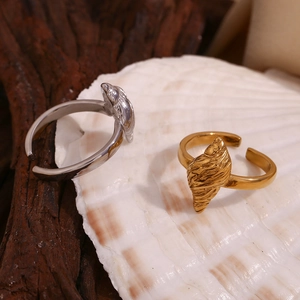 Detailed close-up of conch-shaped open rings in gold and silver finish with natural shell