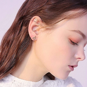 Close-up of a rose gold flamingo stud earring with white crystals on a model ear