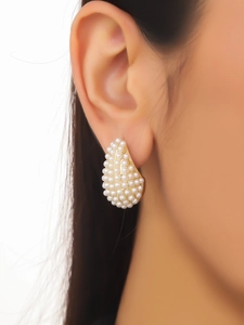 Macro shot of a teardrop-shaped earring featuring densely set white pearls and gold metal edges