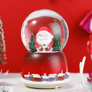 Close-up of a Christmas snow globe music box with Santa Claus and a cozy wooden cabin