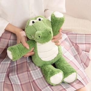 Cute green plush crocodile toy with long legs being held in a cozy home setting