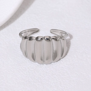 Macro top view of wide silver wavy textured adjustable open ring on white background