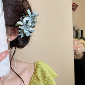 Detail of elegant blue fabric flower hairpin worn on a graceful brunette updo hairstyle