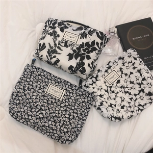 Detailed set of three black and white floral toiletry bags with zipper and logo patch