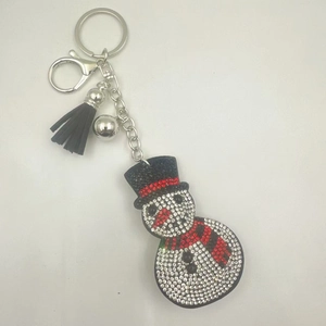 Close-up of snowman keychain with rhinestones, silver bell and black tassel detail