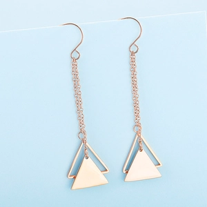 Macro view of rose gold double triangle earrings with long delicate chain tassels