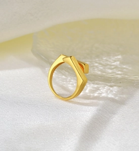 Macro shot of gold geometric cross ring with intricate open design on textured fabric