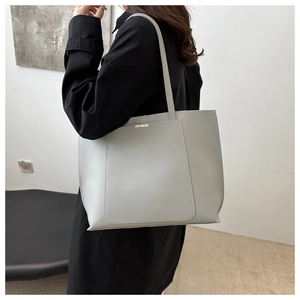 Detail of the grey PU leather tote bag showing smooth texture and silver metal trim