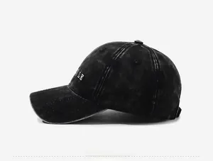 Detailed side view of washed black cotton baseball cap with white letter embroidery