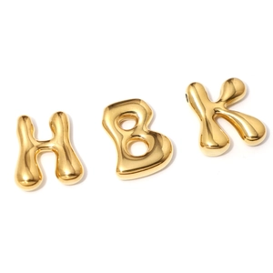 Close-up of 18K gold bubble letters H, K and number 8 charms with shiny metallic finish