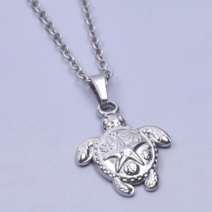 Close-up of turtle pendant with embossed starfish and shell details on silver chain