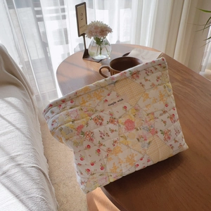 Borsa per trucco trapuntata a fiori con etichetta su un tavolo in legno rustico
