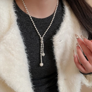 Close-up of a French retro pearl necklace with a Y-shaped glass bead drop pendant