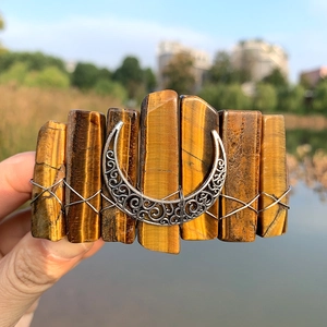 Detail of yellow tiger eye stone hair clip with a silver crescent moon charm accessory
