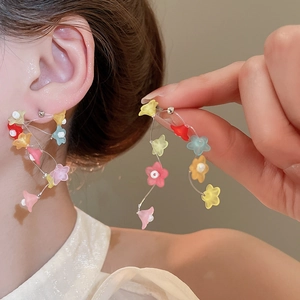 Vue rapprochée de boucles d'oreilles fleurs colorées portées pour un style frais et doux