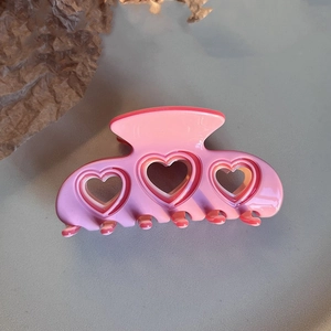 Detail of sweet pink and red layered acetate heart hair claw with cutout heart design