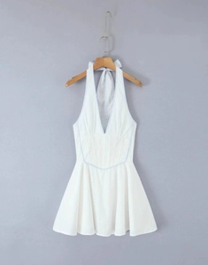 Detail von weißem Neckholder-Minikleid mit gesmokter Taille und tiefem V-Ausschnitt