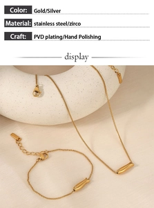 Detailed view of gold fish pendant necklace and bracelet set with cubic zirconia accents