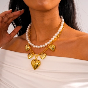 Detail shot of a double-layered necklace with white pearls and gold heart-shaped charms