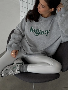 Detail of grey oversized sweatshirt showing green legacy typography and premium cotton texture