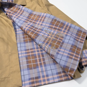 Detail of jacket lining with blue and brown plaid pattern and fine embroidered logo