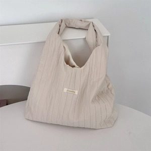 Close-up of pleated beige fabric texture and Sonahka brand label on minimalist shoulder bag