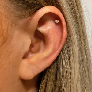 Close-up of a gold crescent moon helix earring with pearl on female model ear