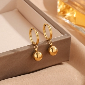 Gold titanium steel hoop earrings with polished ball charms on a jewelry box display