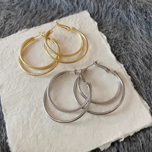 Set of gold and silver double-layered interlaced hoop earrings on textured white card