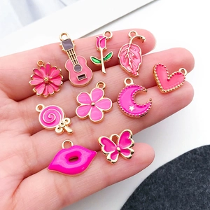 Detail of pink and gold alloy charms including butterfly, heart, and flower on a hand