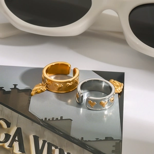Detail of gold heart embossed open ring on artistic background with sunglasses