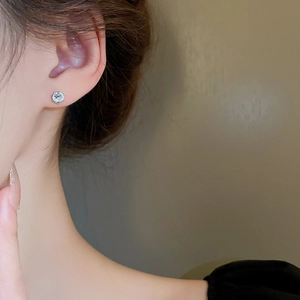 Macro detail of round brilliant-cut zircon stud earring with classic prong setting