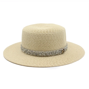 Detailed close-up of straw boater hat with shimmering sequins and gold M metal logo