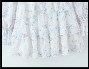 Détail de volants superposés et d'imprimé feuilles bleu clair sur robe en mousseline