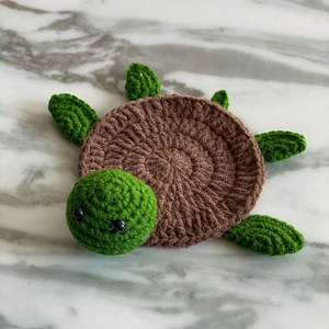 Detail showing the intricate crochet texture of the handmade green turtle coaster
