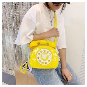 Detailed view of yellow patent leather handbag shaped like a vintage rotary telephone