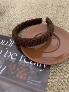 Close-up of thick knitted dark brown headband featuring warm autumn wool texture
