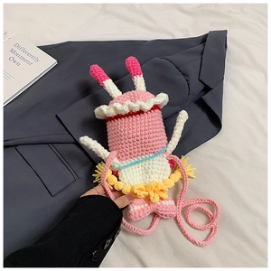 Close-up of handmade pink crochet phone bag with white wing accents and knitting texture