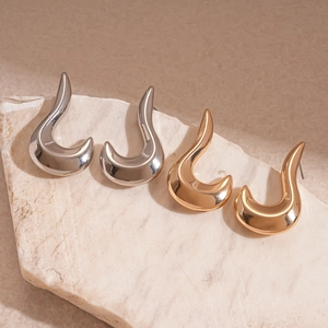 Minimalist irregular geometric metal stud earrings in gold and silver finish on a stone base