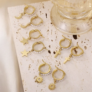 Elegante goldene Creolen mit Perlen und Himmelskörper-Anhängern auf Steinbasis