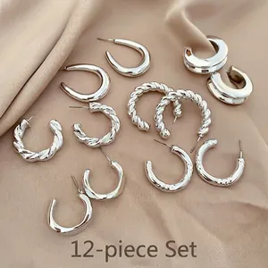 Close-up of a 12-piece silver C-shaped earring set on elegant beige satin fabric